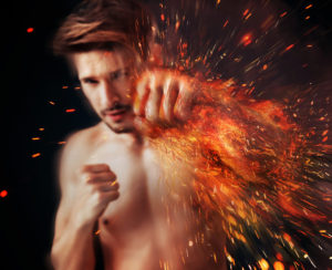 Handsome athlete punching with flame around his arm